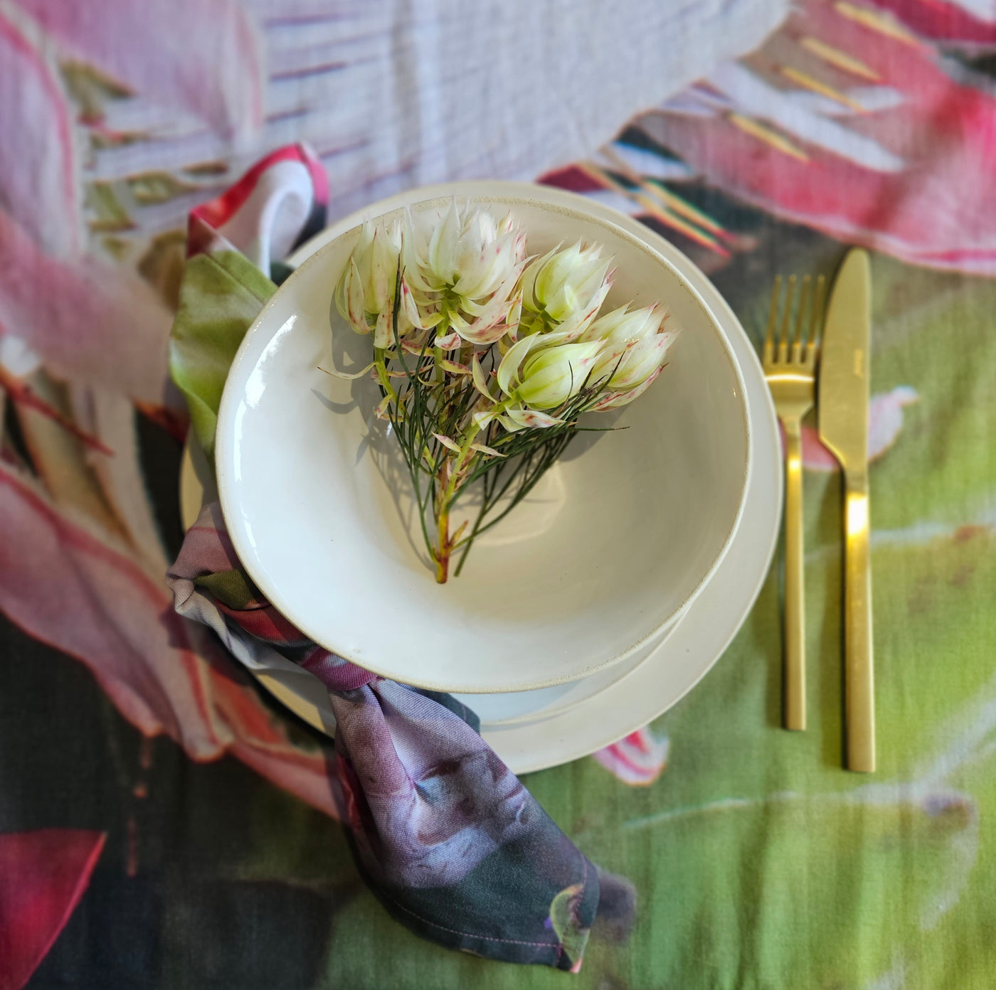 Flowers in a bowl with golden utensils on a flower tablecloth