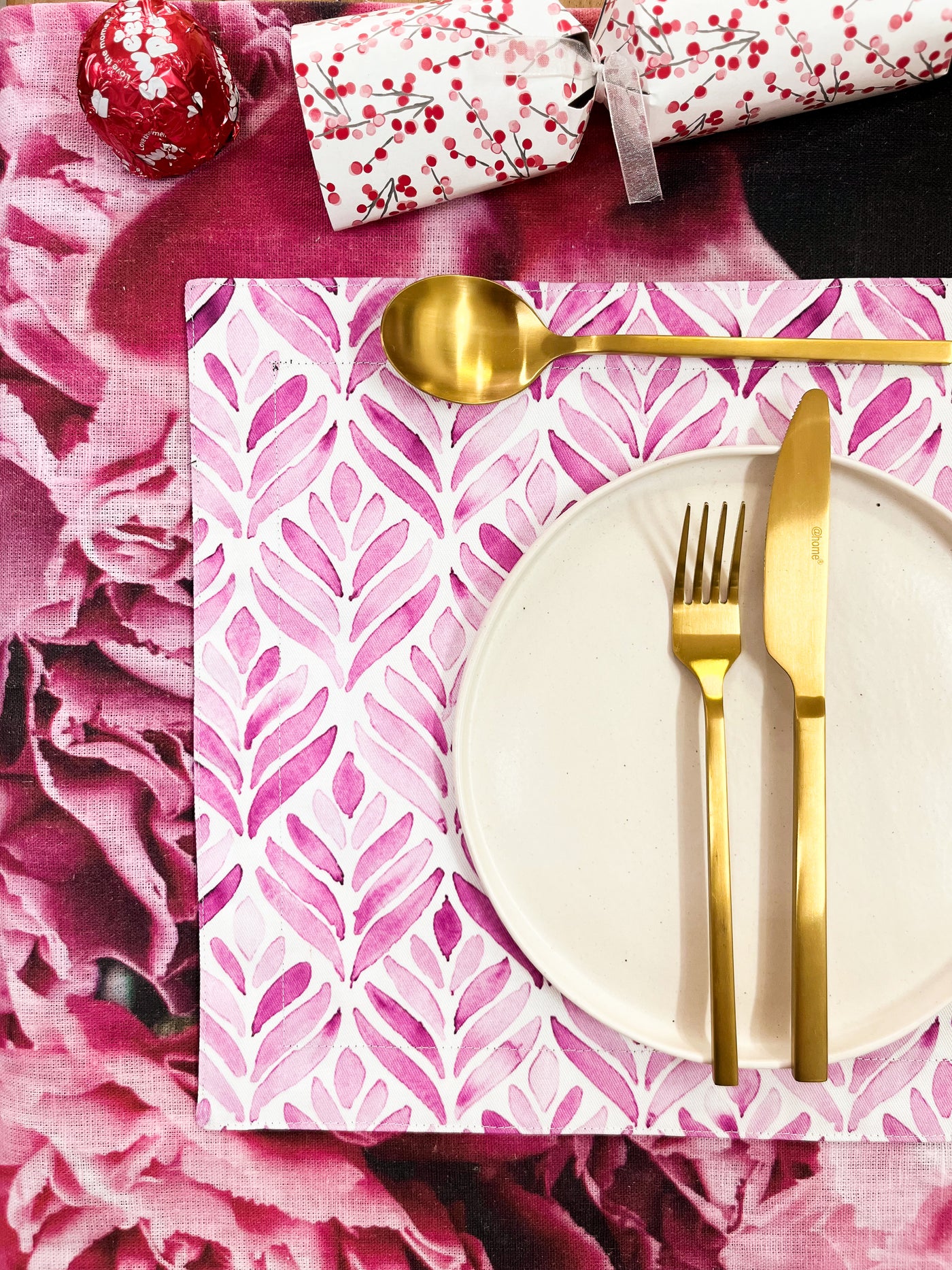 Golden Utensils on White Crockery on Flower Placemat on Floral Tablecloth