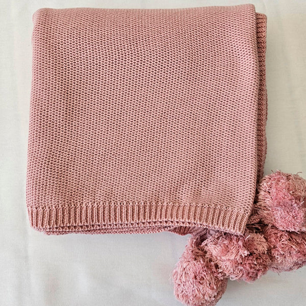 pink blanket with pompoms